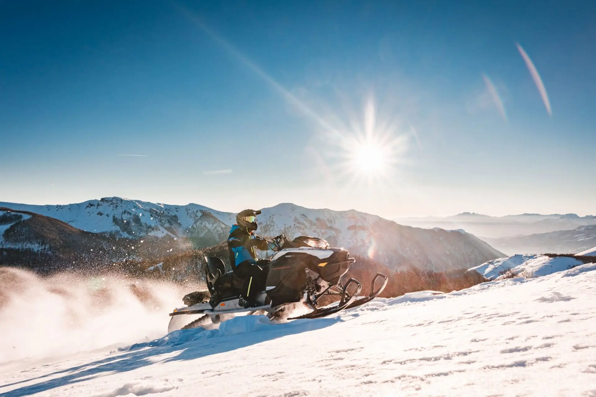 Snowmobile rider crossing a sunlit snowy slope on Bjelasica