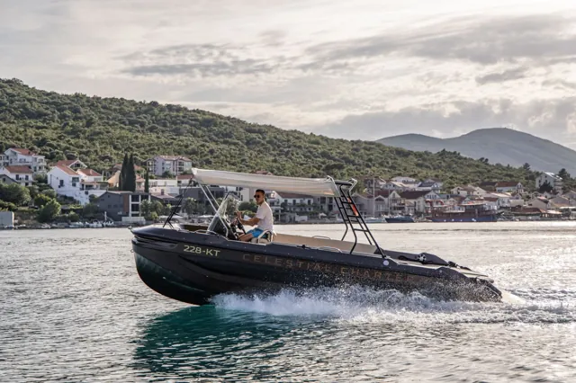 Private tour boat crossing Boka Bay with the waterfront behind it
