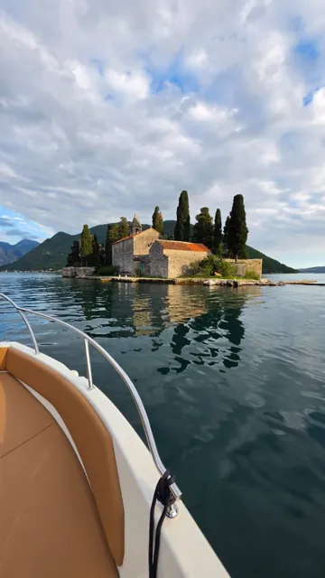 Island monastery and cypress trees seen from a boat in Boka Bay