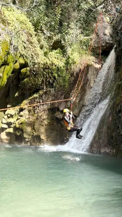 Canyoneer rappelling beside a waterfall