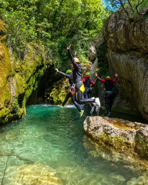 Canyoning group jumping into a clear Drenostica pool