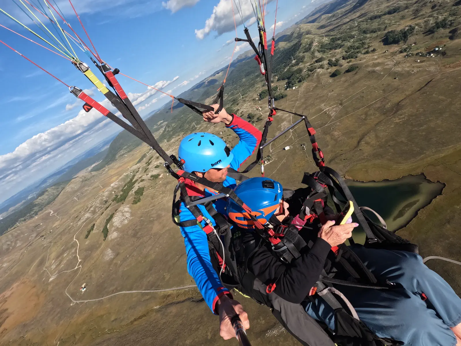 Tandem paragliding with a glacial lake visible below in Durmitor