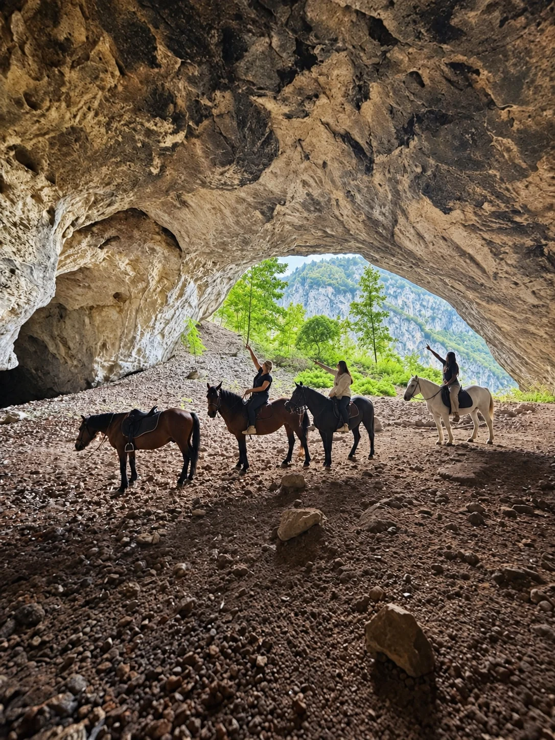 Horse riders beneath the broad entrance of Đurova Cave in Dobrilovina