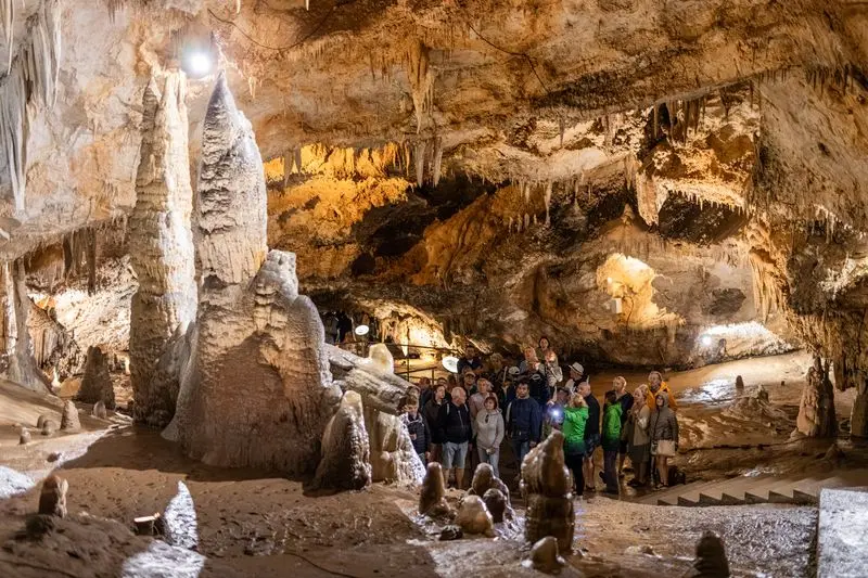 Guided visitor group beside limestone formations in Lipa Cave