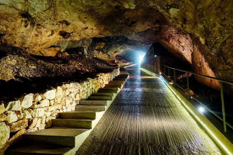 Illuminated walkway leading into Lipa Cave