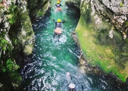 Canyoning participants swimming through a narrow turquoise channel