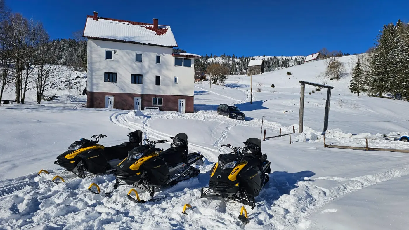 Snowmobiles prepared beside a winter lodge near Žabljak